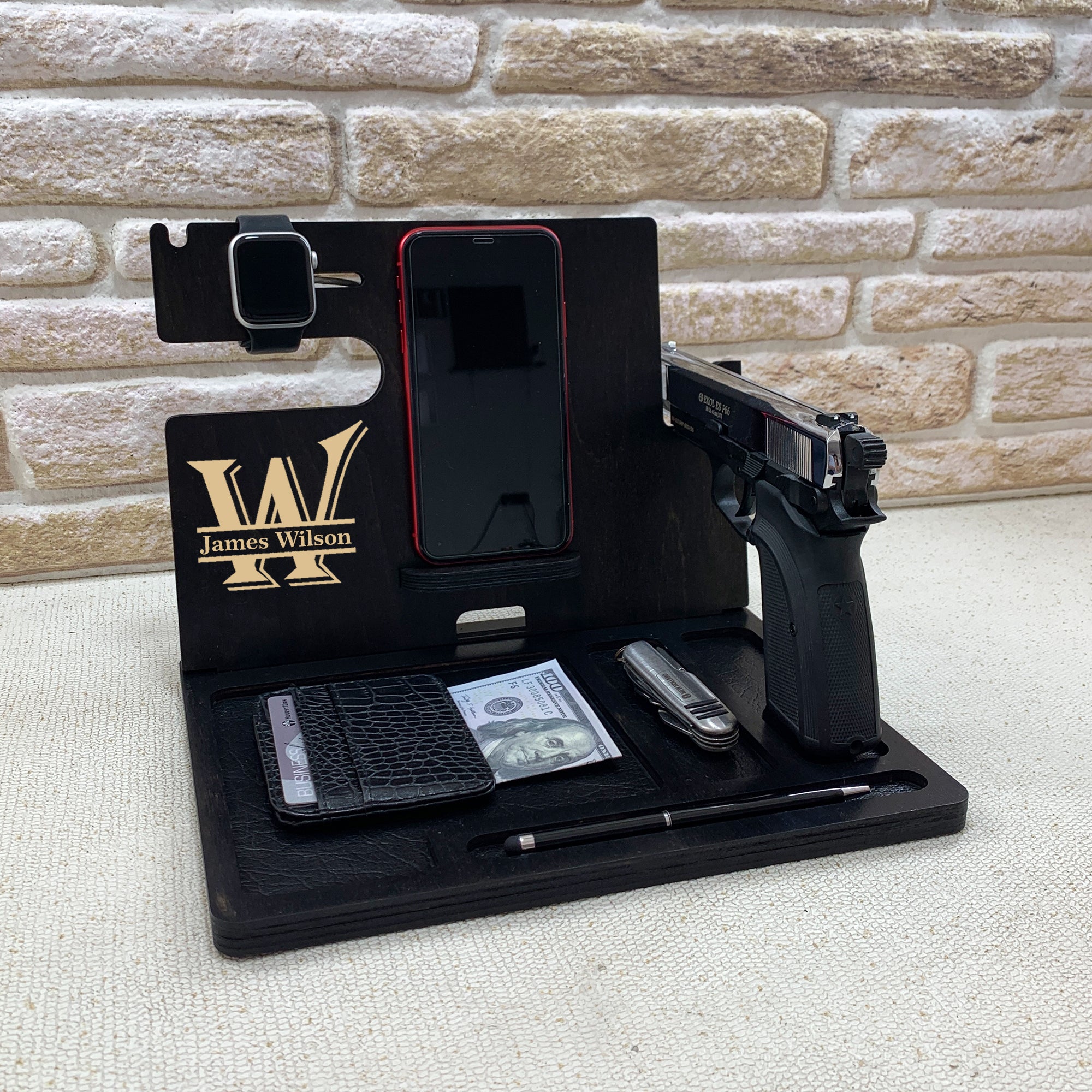 Personalized black wooden nightstand valet with custom engraved initial and name. Personalized gifts for police officer which include holders for an Apple Watch, smartphone, wallet, pen, and a dedicated slot for a handgun. The stand is organized to keep everyday carry items neatly in place. ideal gifts for law enforcement, police retirement and the one who have gun. 